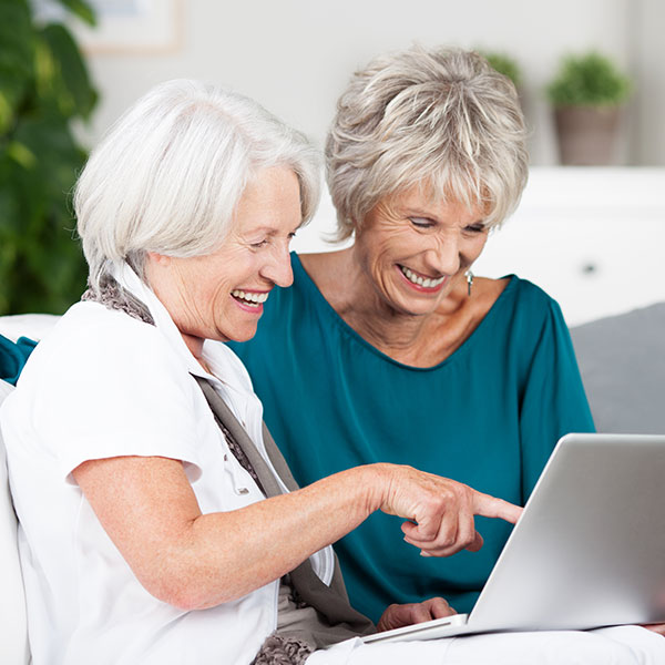 Two senior ladies looking at a laptop.