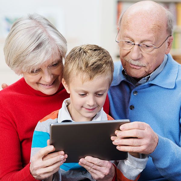 Two seniors looking at a tablet with a child.