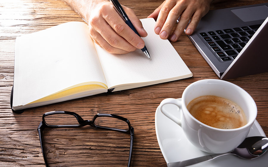 A photo of a person writing in a notepad.